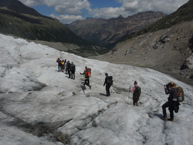 Das Bild zeigt 10 Teilnehmerinnen und Teilnehmer auf einer Gletschertour des Seminars. Sie laufen in einer Reihe hintereinander über den Gletscher.