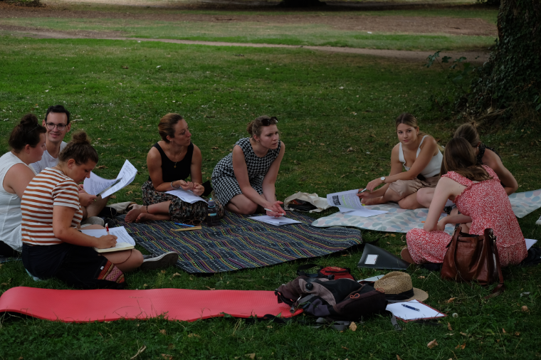Auf einer Literaturexkursion diskutieren 6 Referendarinnen und ein Referendar, die im Kreis sitzen, im Tübinger Stadtpark die Ergebnisse ihrer Arbeitsgruppen.
